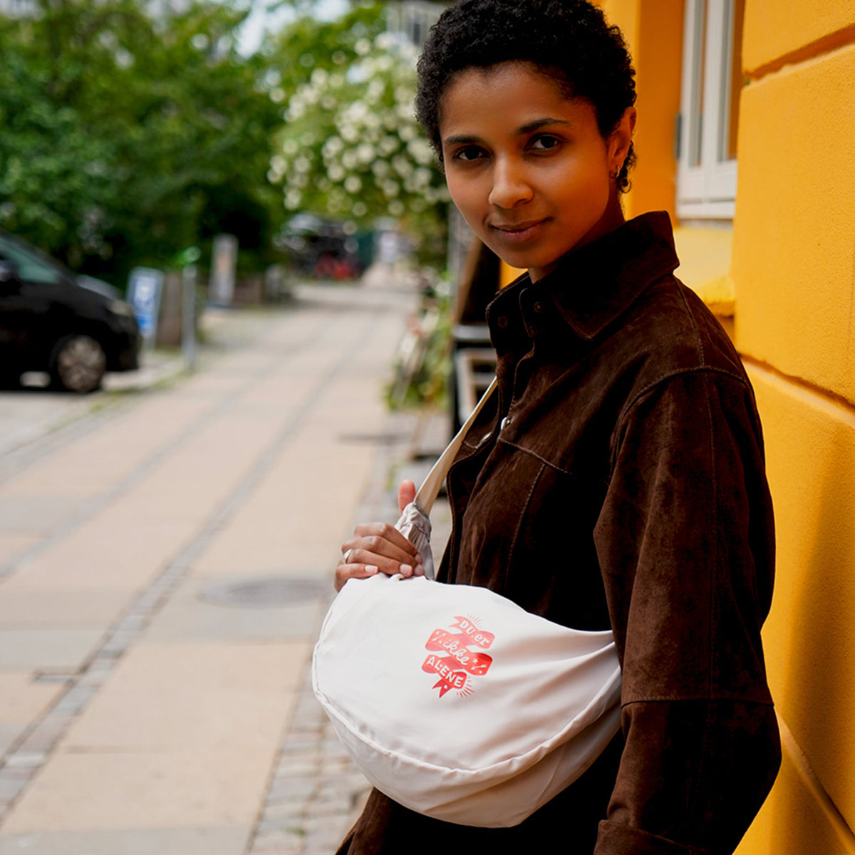 Du er ikke Alene - ung kvinde iført slingbag fra Folkekirkens Nødhjælps sommerkollektion.