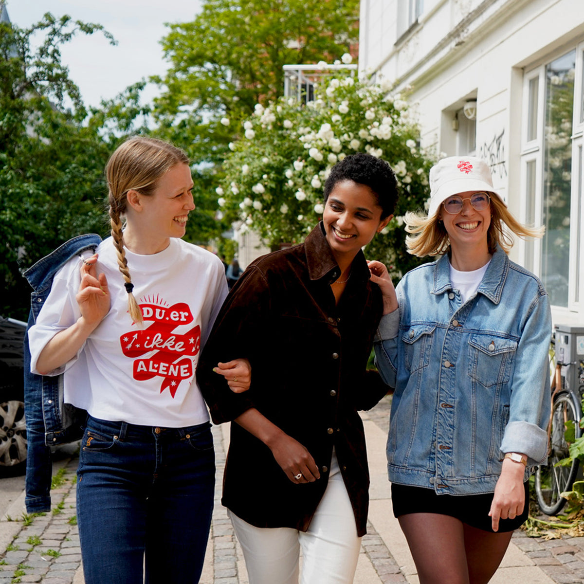 Du er ikke Alene - Tre unge kvinder går på gaden iført produkter fra Folkekirkens Nødhjælps sommerkollektion.